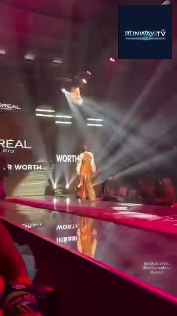 A model walking the red runway under the L'Oréal Paris show lights for RUNWAY TV